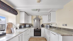 A modern kitchen with white cabinets, a stainless steel range hood, a built-in oven, a microwave, and a sink.