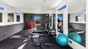 Un gimnasio con equipo de ejercicio, una maleta roja y una pelota de ejercicio azul grande.