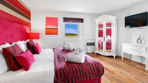 Habitación de hotel con cama, armario, televisor y ventana con vista al campo.