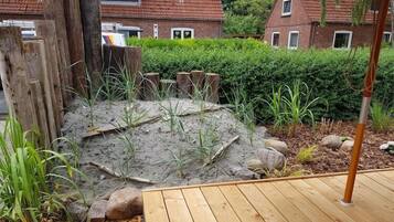 A wooden deck with a small garden area featuring a wooden fence, rocks, and plants.