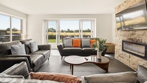A modern living room with leather sofas, a coffee table, and a stone fireplace.