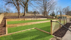 A garden with raised beds, a wooden fence, and a metal railing.