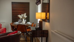 A dining area with a wooden table, chairs, and a vase of flowers. - Stable Cottage - North East Escapes (Bamburgh)