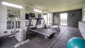 Une salle de sport à domicile équipée d’un tapis de course, d’un vélo elliptique et d’un vélo d’exercice.