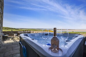 A hot tub with two glasses and a bottle of wine, set against a scenic outdoor view.