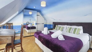 Un dormitorio con una cama grande, un escritorio de madera y una silla. Hay un espejo en la pared y una lámpara en el techo.