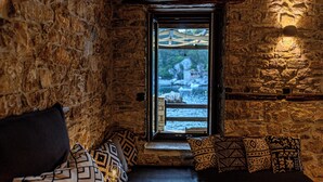 A stone-walled room with a built-in bench and patterned cushions. - Cleopatra's Miramare (Zagora-Mouresi)