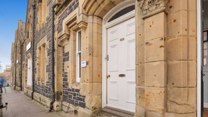 A historic building with a white door, stone facade, and a small window.