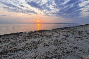 A beach with a sunset over the water.