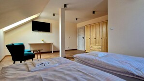Een hotelkamer met twee bedden, een bureau, een stoel en een aan de muur bevestigde televisie.