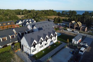 A residential area with multiple houses, a paved driveway, and a view of the sea.