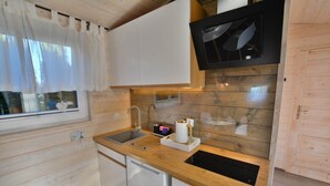 A compact kitchen with wooden cabinetry, a built-in microwave, a sink, and a dishwasher. - Year-round, modern holiday home with a terrace (Ustronie Morskie)