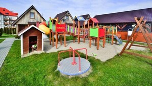 A playground with a swing set, climbing structures, and a merry-go-round. - Year-round, modern holiday home with a terrace (Ustronie Morskie)