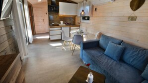 A cozy cabin interior with a dining area, kitchenette, and a blue sofa. - Comfortable holiday home with a terrace, Ustronie (Ustronie Morskie)