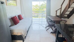 A bedroom with a bed, a desk, and a staircase. - Namaste Flats (Imbituba)