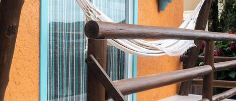 A wooden staircase with a hammock, a window with blue trim, and a potted plant on the wall.