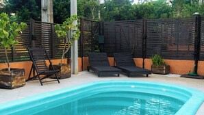 A swimming pool with lounge chairs and a wooden fence. - Namaste Flats (Imbituba)