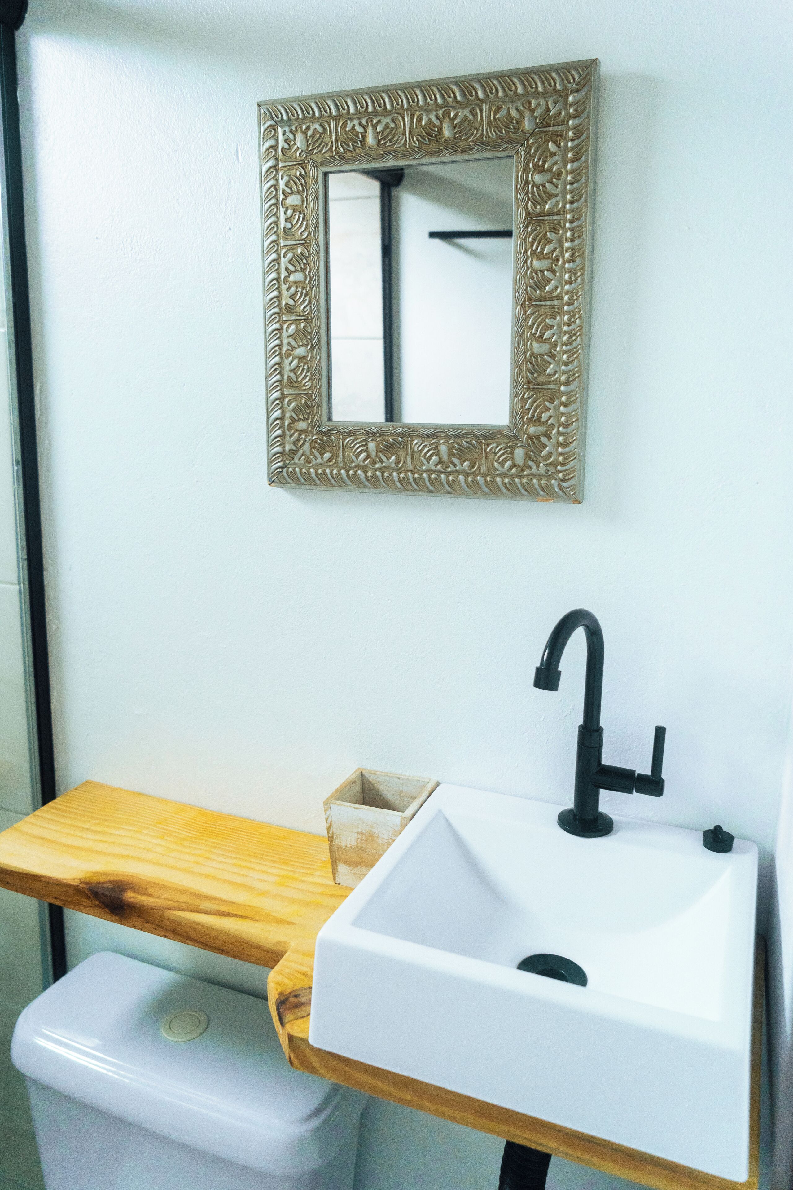 A bathroom with a white sink, black faucet, and a wooden countertop.