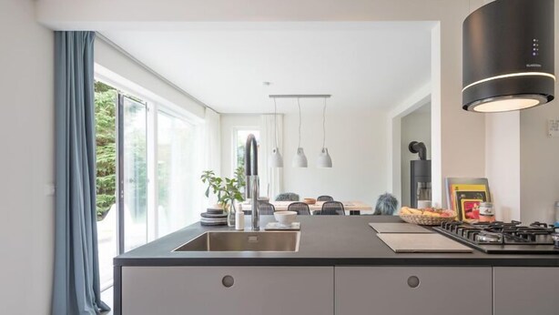 Una cocina moderna con una isla grande, electrodomésticos de acero inoxidable e iluminación colgante.