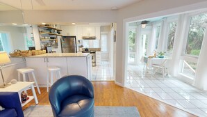 Een moderne keuken met witte kastjes, een roestvrijstalen koelkast en een eethoek met een tafel en stoelen.