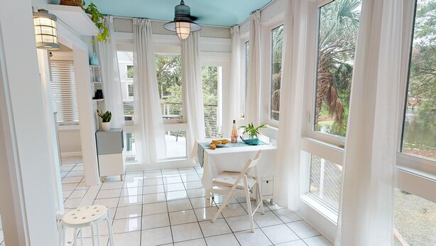 Een lichte, zonnige kamer met een wit gedekte tafel, grote ramen en uitzicht op het groen.