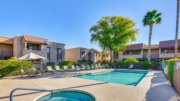 A pool area with lounge chairs and a hot tub, surrounded by apartment buildings and palm trees. - 2BR Gated Condo Near Old Town | Pool + Gym (Scottsdale)