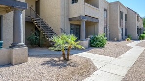 A multi-story building with a central staircase, outdoor seating, and a palm tree. - 2BR Gated Condo Near Old Town | Pool + Gym (Scottsdale)