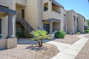 A multi-story building with a central staircase, outdoor seating, and a palm tree. - 2BR Gated Condo Near Old Town | Pool + Gym (Scottsdale)
