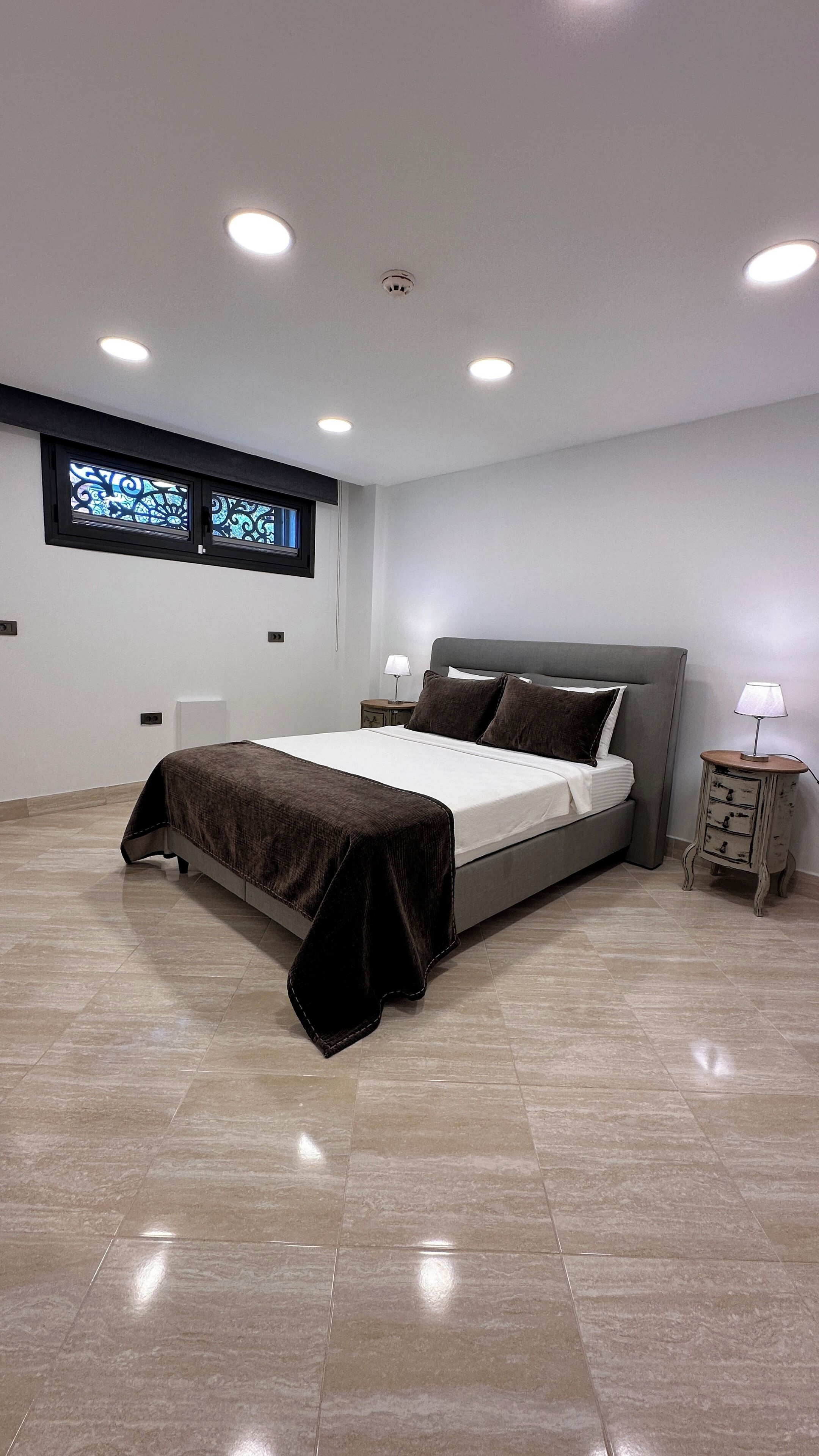 A modern bedroom with a bed, nightstands, and a window.