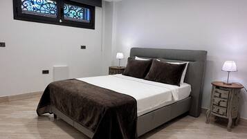 A modern bedroom with a bed, nightstands, and a window.