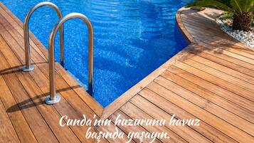 Een buitenzwembad, parasols bij het zwembad en ligstoelen