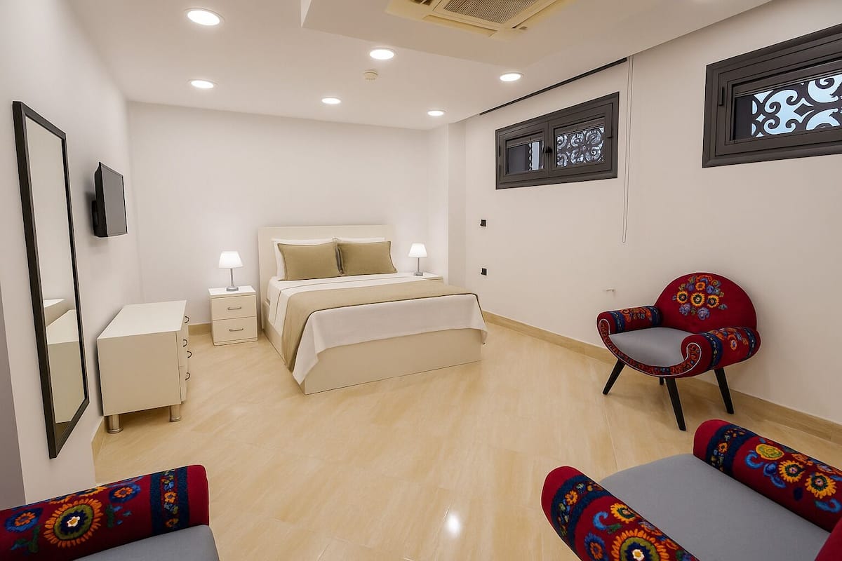 A bedroom with a bed, bedside tables, a chair, and a sofa.