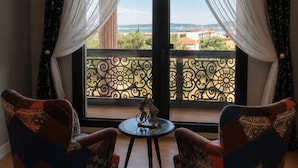 Una habitación con dos sillas estampadas, una mesita y vistas a un balcón con barandilla.