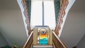 Una escalera de madera con vistas a un ventanal de vidrio emplomado lleno de colores.