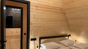 Una stanza con pannelli in legno, un letto, lampade sui comodini e una porta che dà su un'altra stanza.