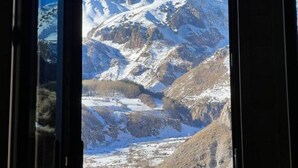 Vista di montagna attraverso un ingresso, con una cima innevata e terreno roccioso.