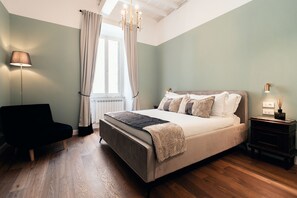 A bedroom with a bed, a chair, a nightstand, and a lamp. - Naman Hotellerie Monti (Rome)