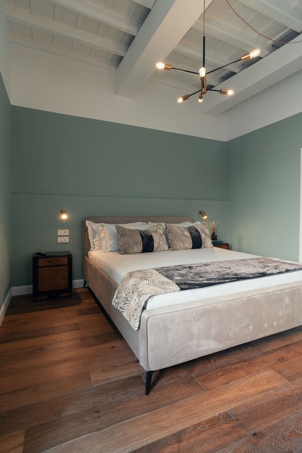 A bedroom with a large bed, wooden flooring, a ceiling light fixture, and a nightstand with a lamp. - Naman Hotellerie Monti (Rome)
