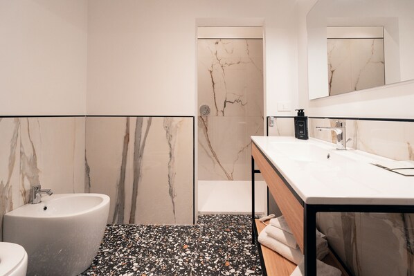 Une salle de bain moderne avec un mur en marbre, un lavabo et une baignoire.