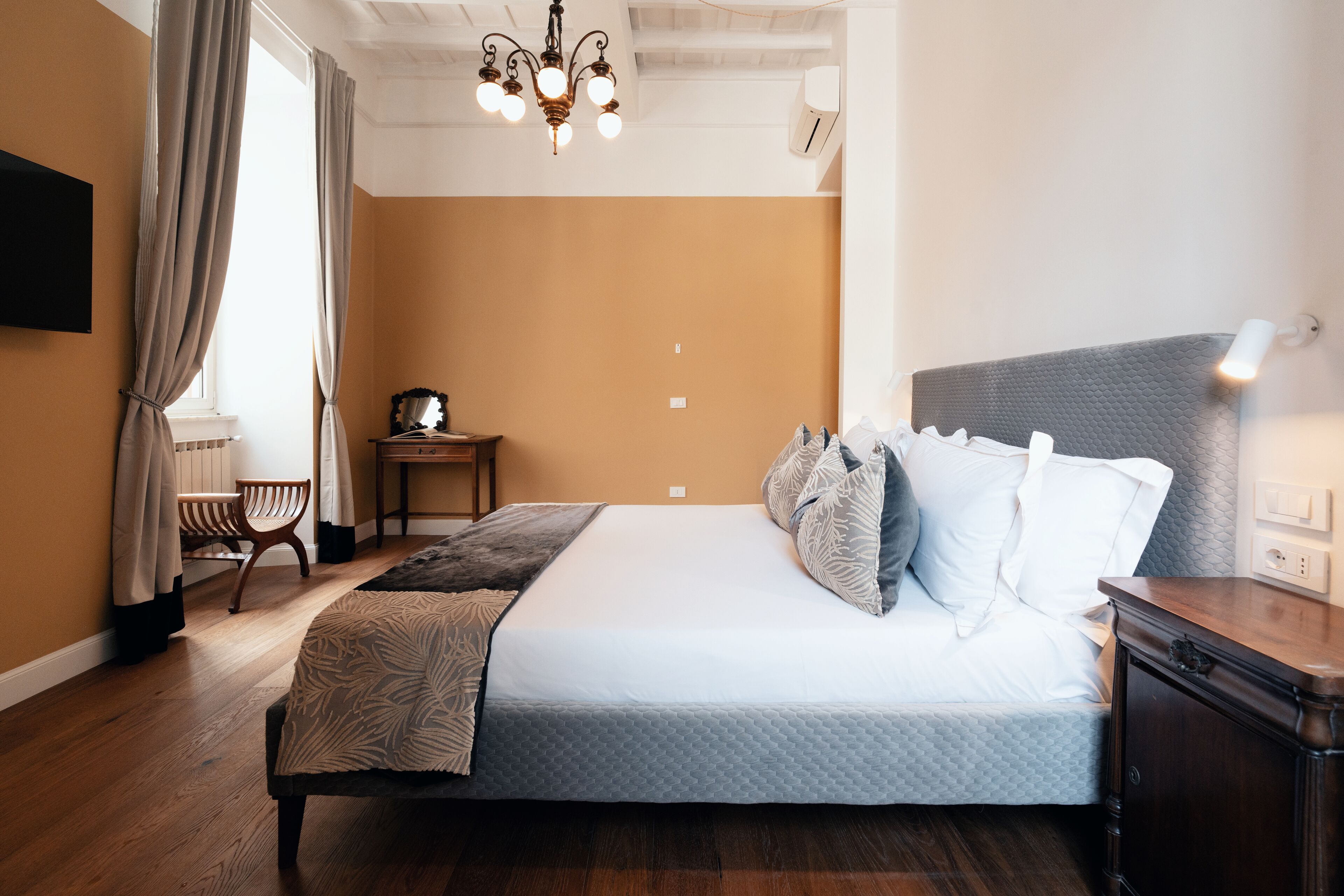 A neatly arranged bedroom with a large bed, a bedside table, a chair, and a hanging light fixture.