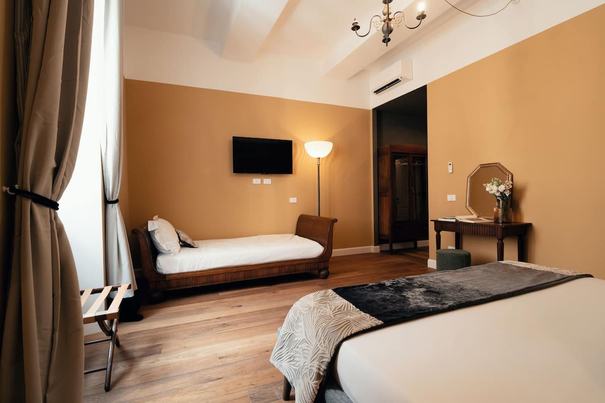 A hotel room with a single bed, a bedside table, a lamp, and a TV mounted on the wall.
