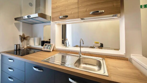 A modern kitchen with a wooden countertop, stainless steel sink, and built-in cabinets. - Spacious and Modern Apartment in the Heart of Rome
 (Roma)