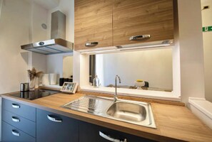 A modern kitchen with a wooden countertop, stainless steel sink, and built-in cabinets. - Spacious and Modern Apartment in the Heart of Rome
 (Roma)