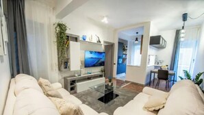 A modern living room with a sofa set, a flat-screen TV, and a dining area with a table and chairs. - Spacious and Modern Apartment in the Heart of Rome
 (Roma)