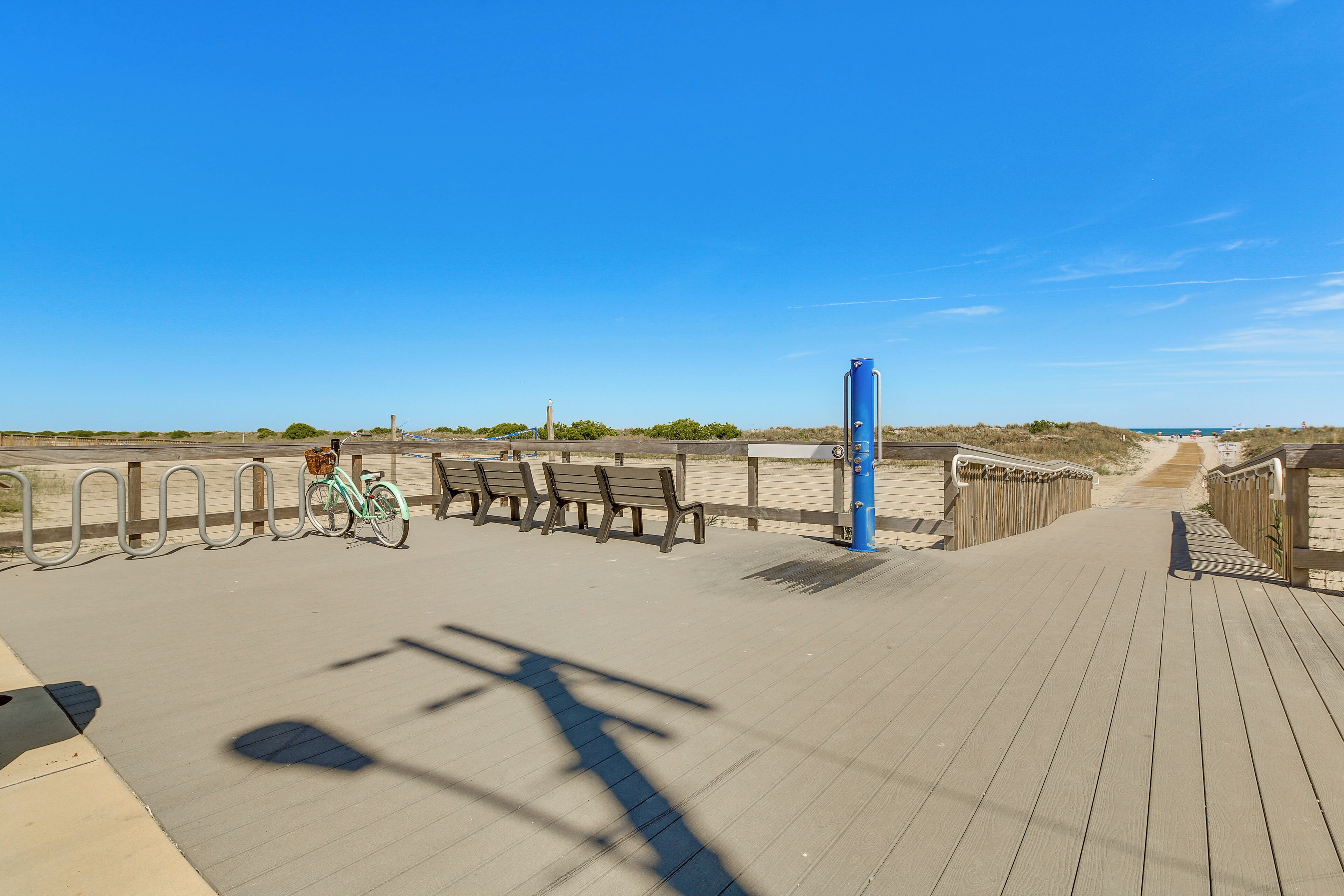 A wooden boardwalk with benches and a bicycle rack.