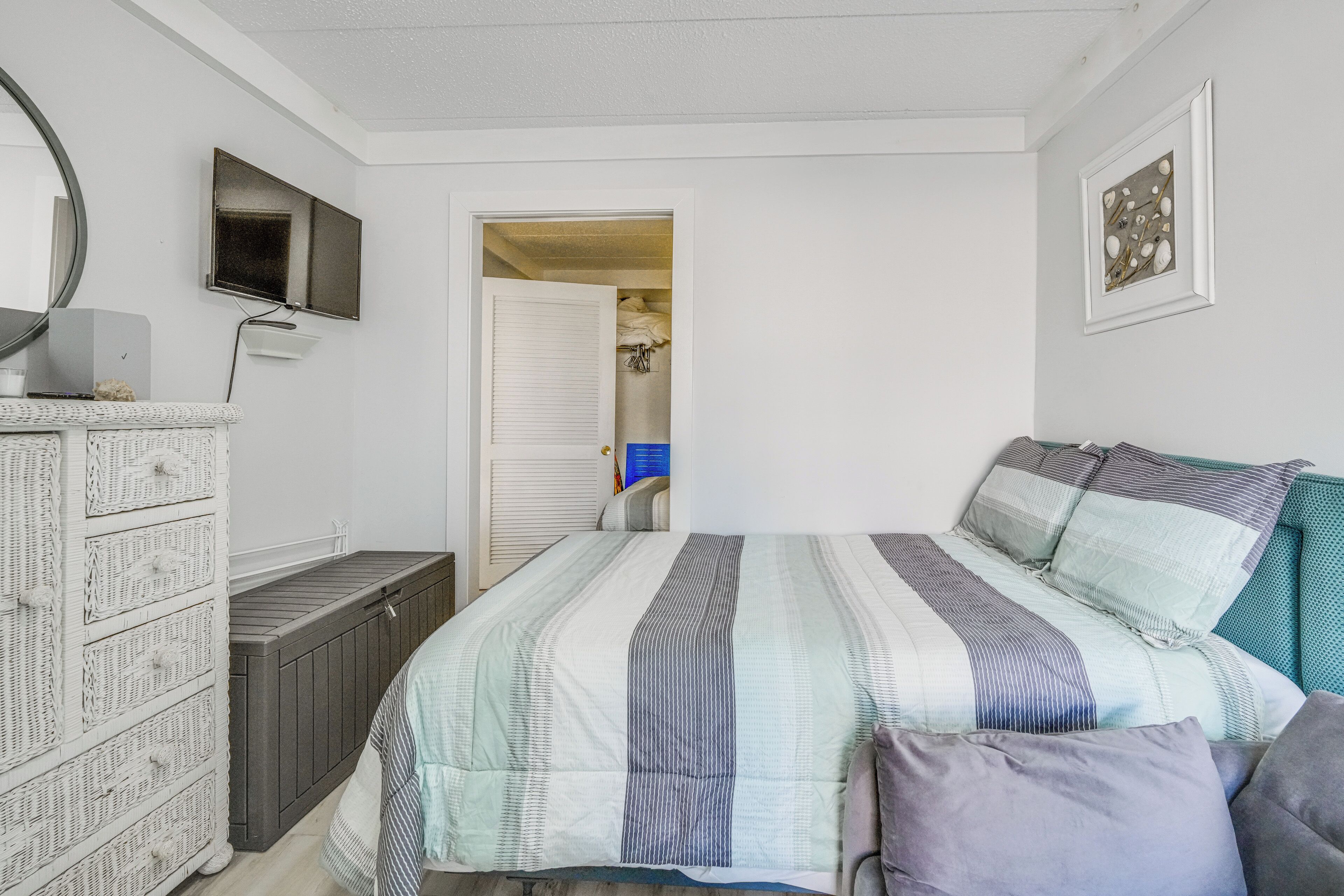 Une chambre à coucher comprenant un lit, une commode, un téléviseur et des œuvres d’art.