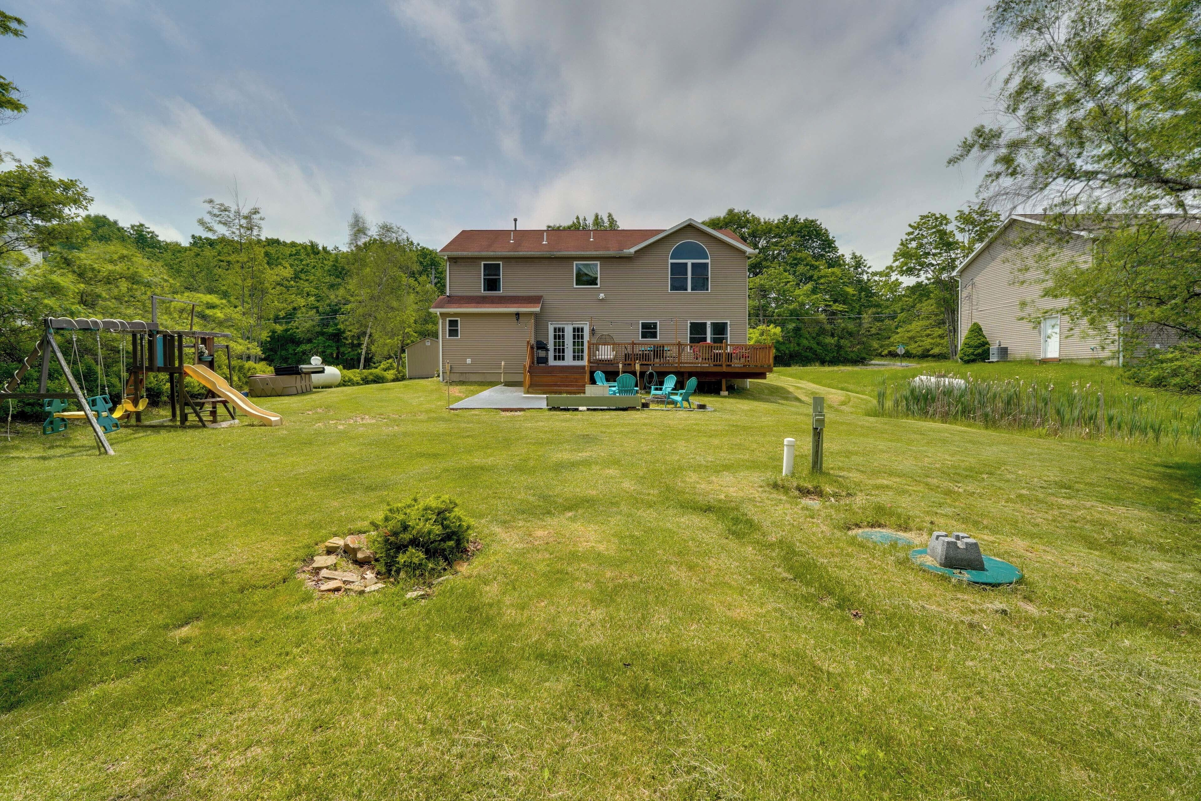 A two-story house with a deck, a play area, and a well-maintained lawn.