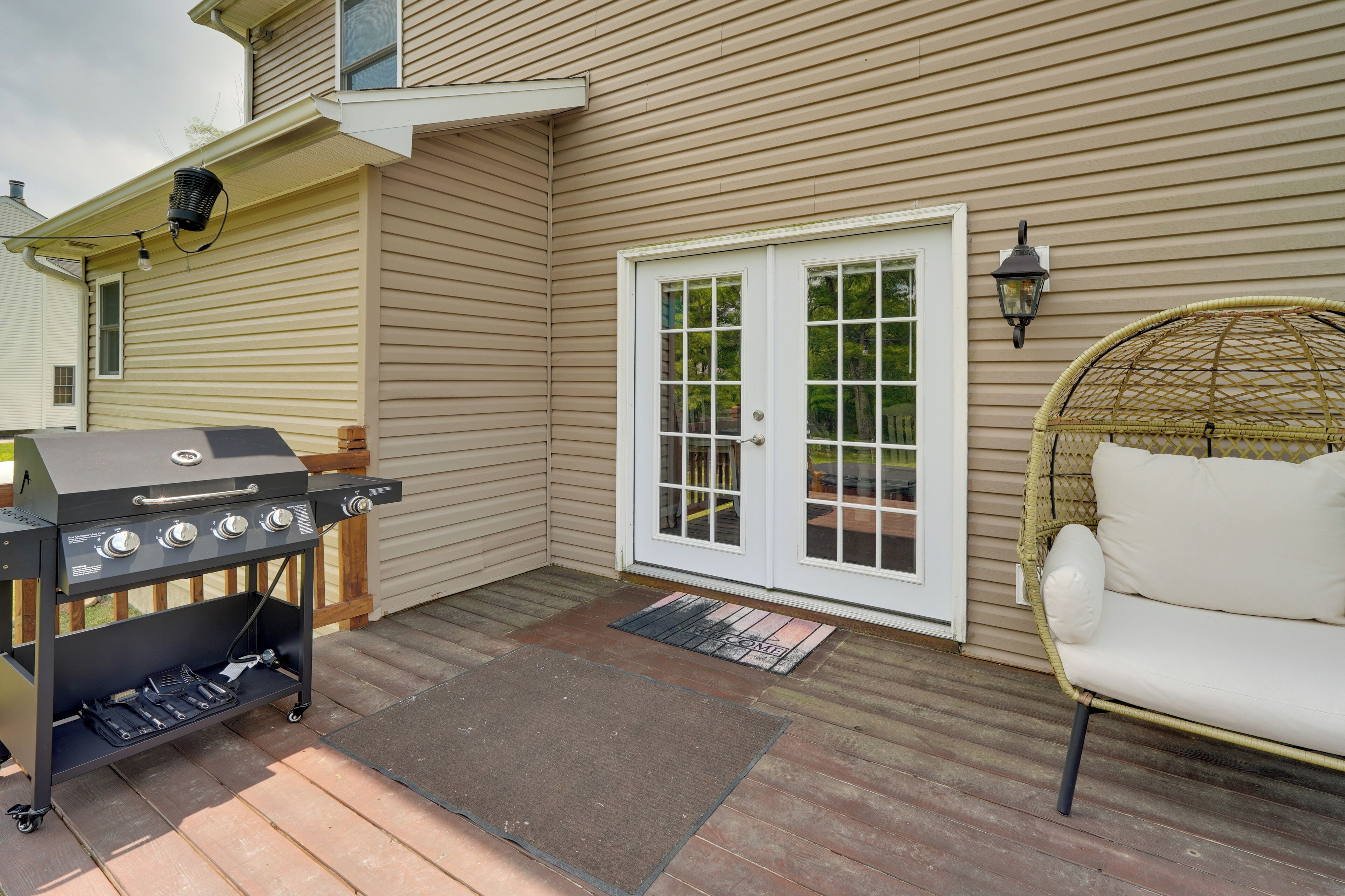 A patio with a grill, a wicker chair, and a door with glass panels.