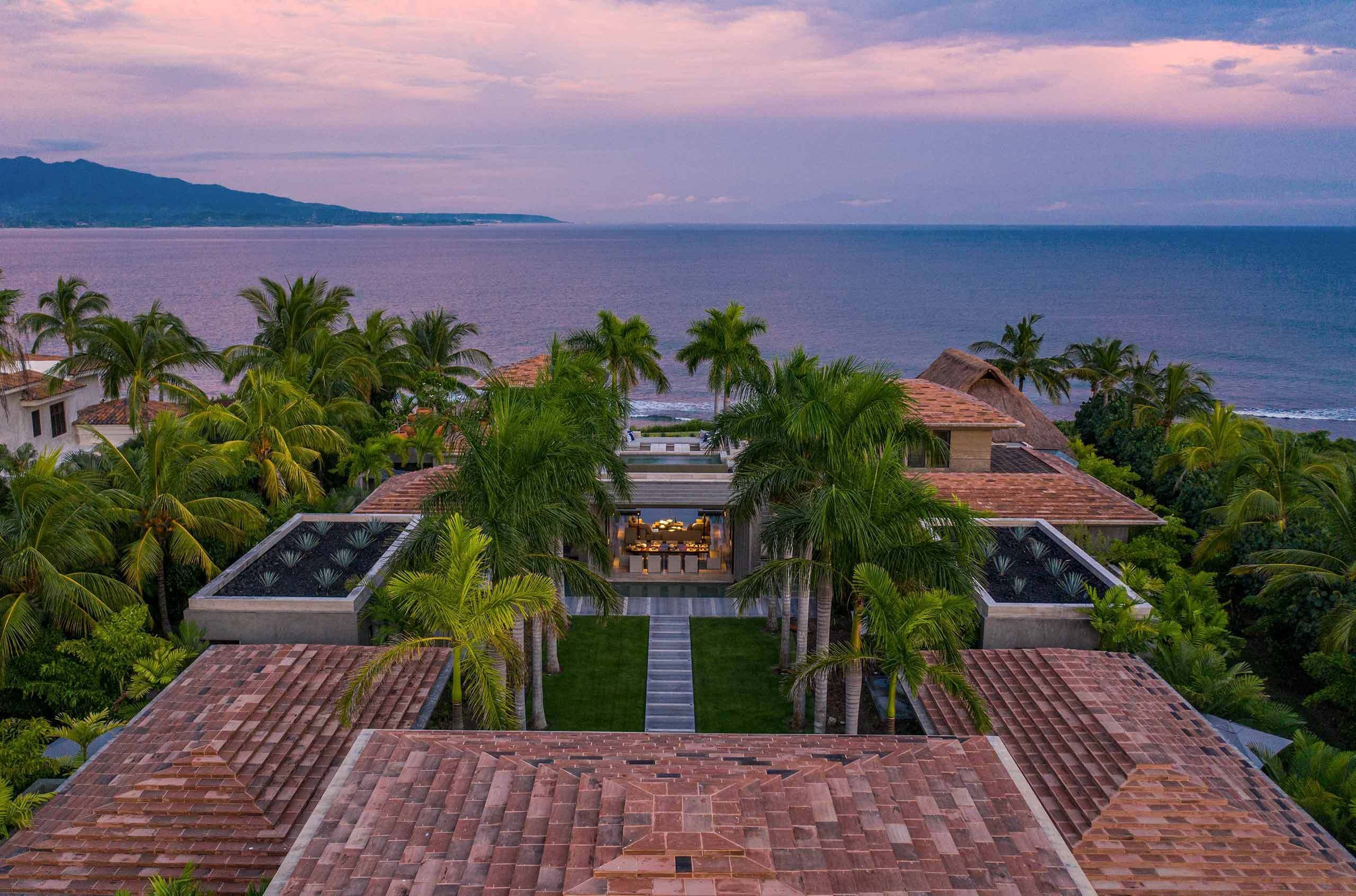 A resort with a view of the ocean, palm trees, and a pool area.