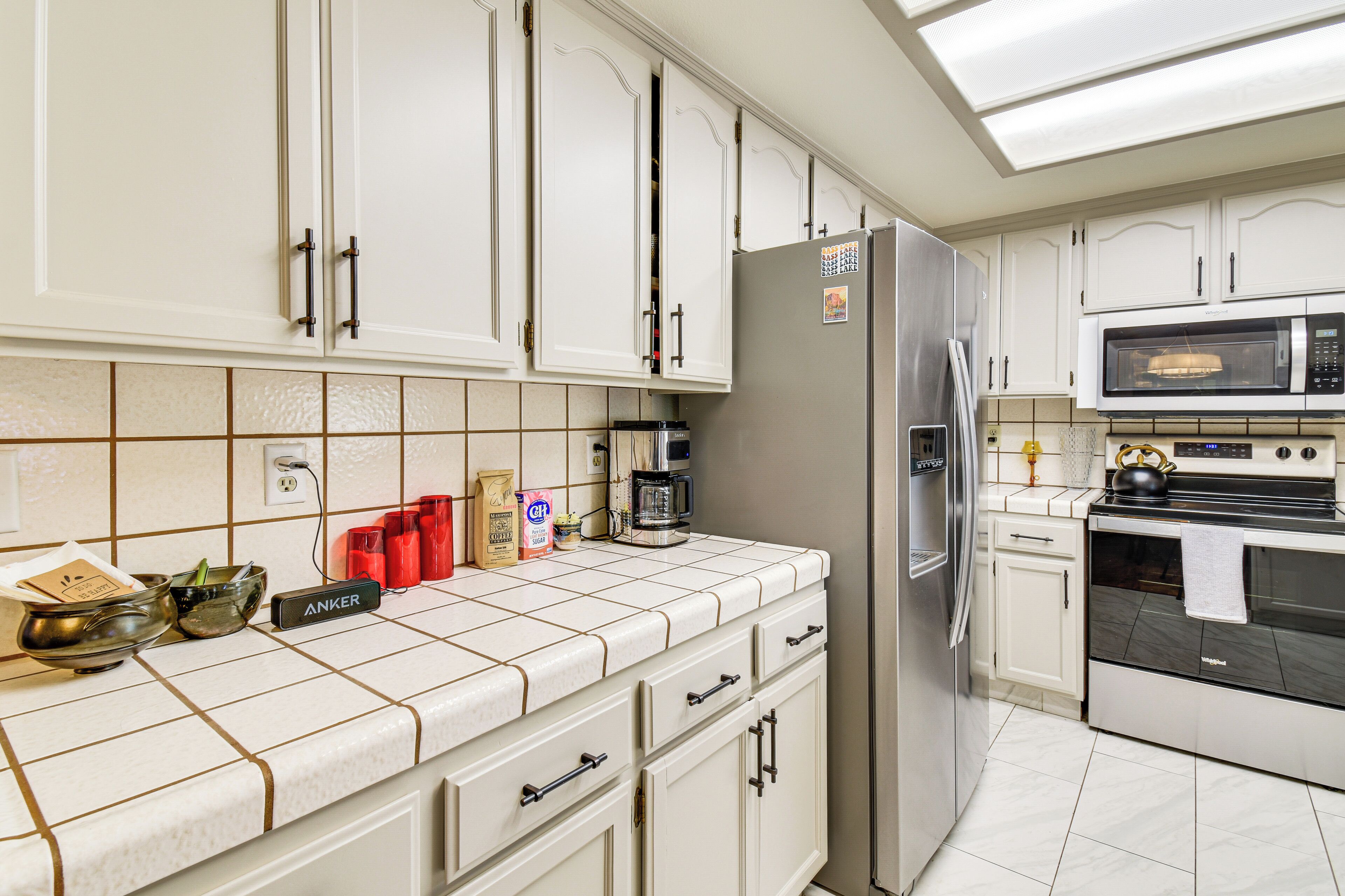 A modern kitchen with white cabinets, stainless steel appliances, and a tiled backsplash.